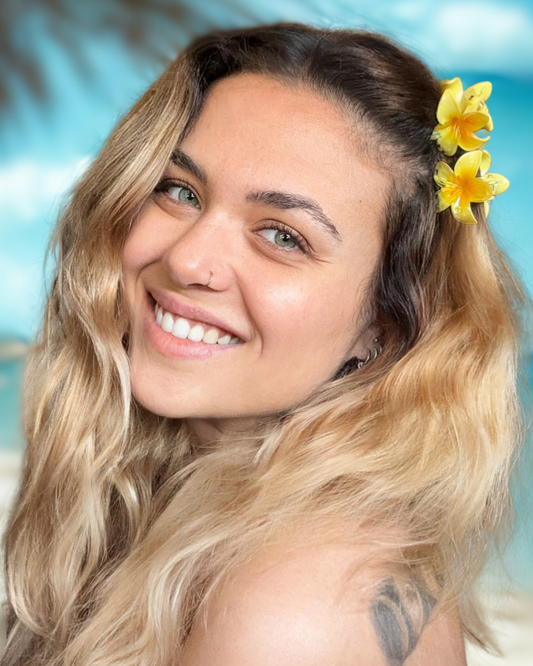 Woman with a flower in her hair smiling on a beach