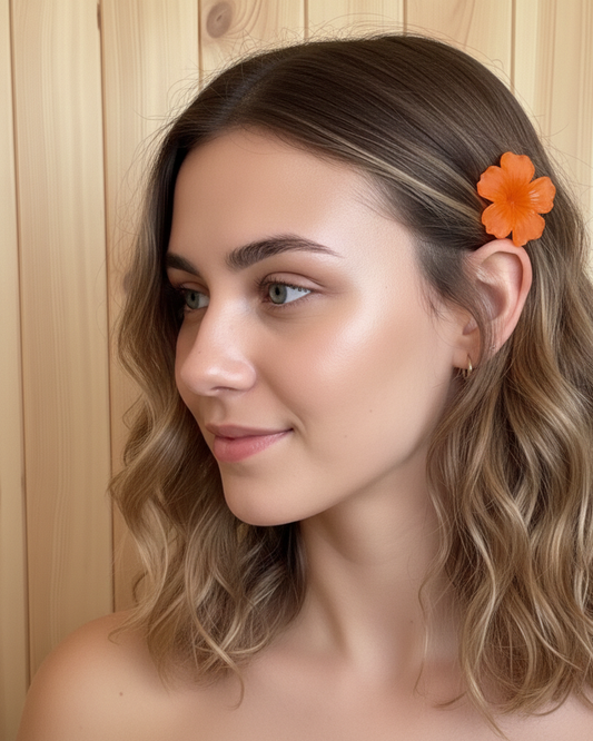 Woman with wavy hair and an orange flower clip against a wooden background