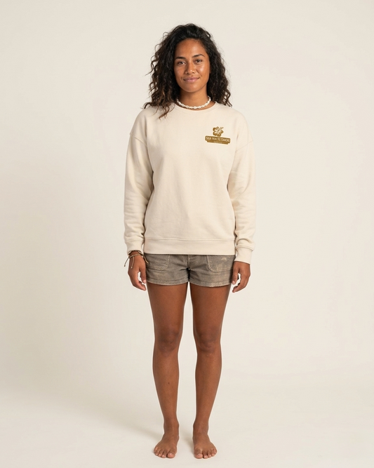 Person wearing a beige sweatshirt with a logo on a plain background