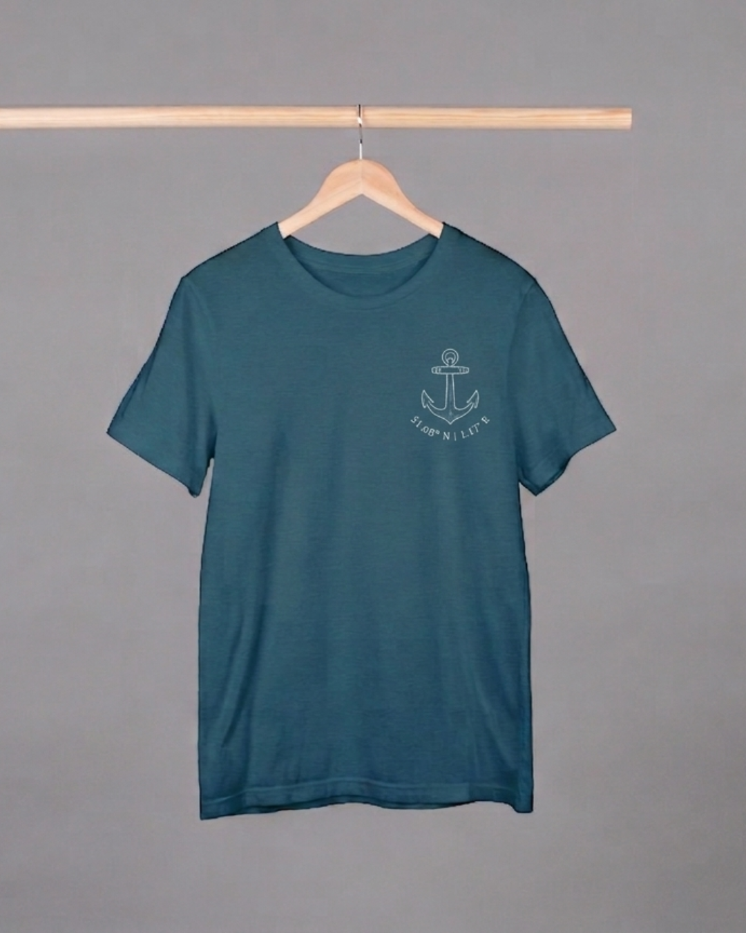 Teal t-shirt with an anchor design on a hanger against a gray background