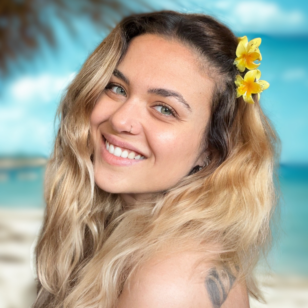 Woman with a flower in her hair smiling on a beach