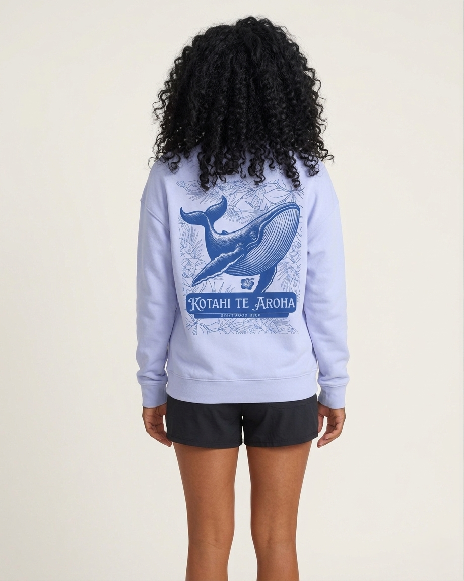 Person wearing a light blue sweatshirt with a whale design and text on the back, standing against a plain background.