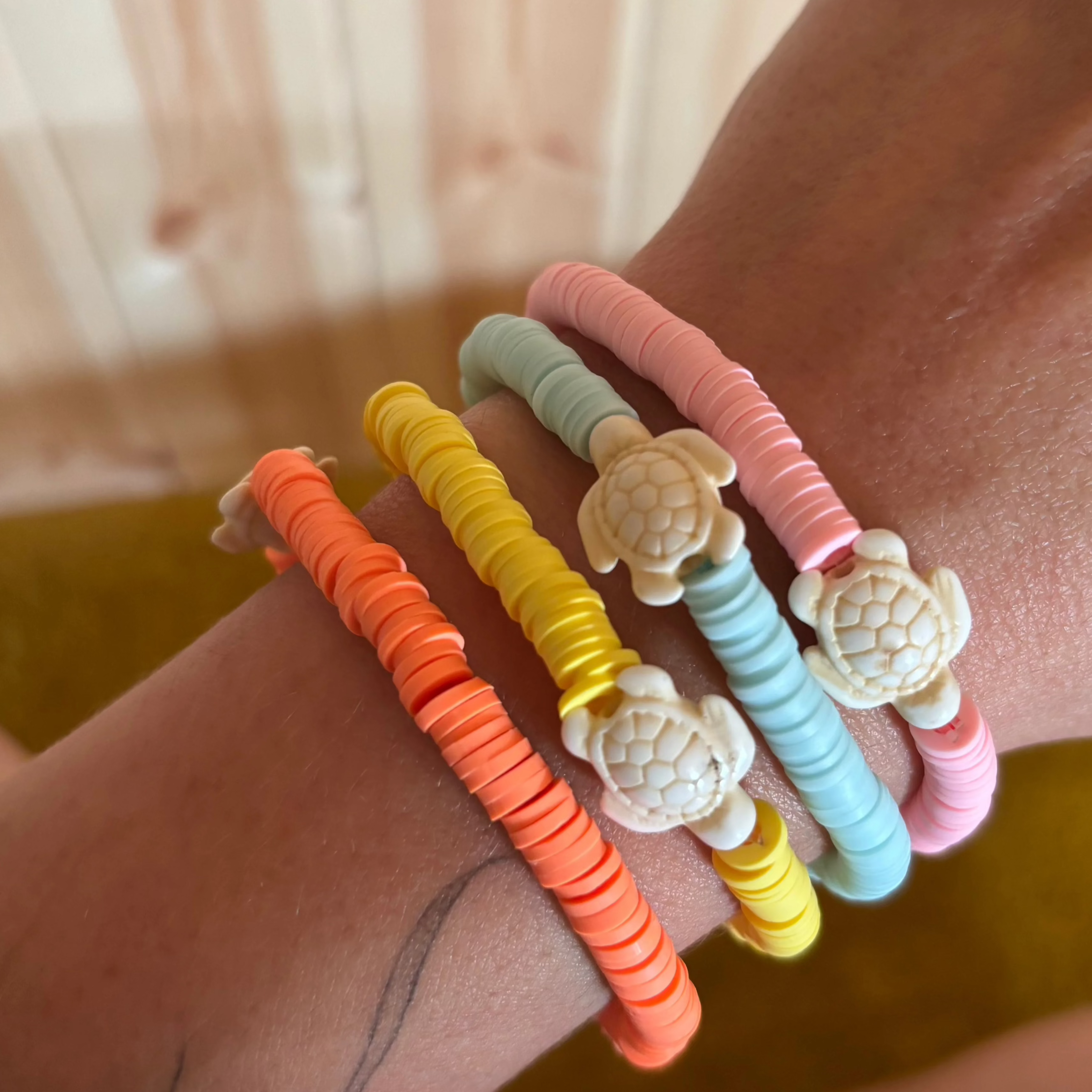 Colourful bracelets with turtle charms on a wrist against a blurred background