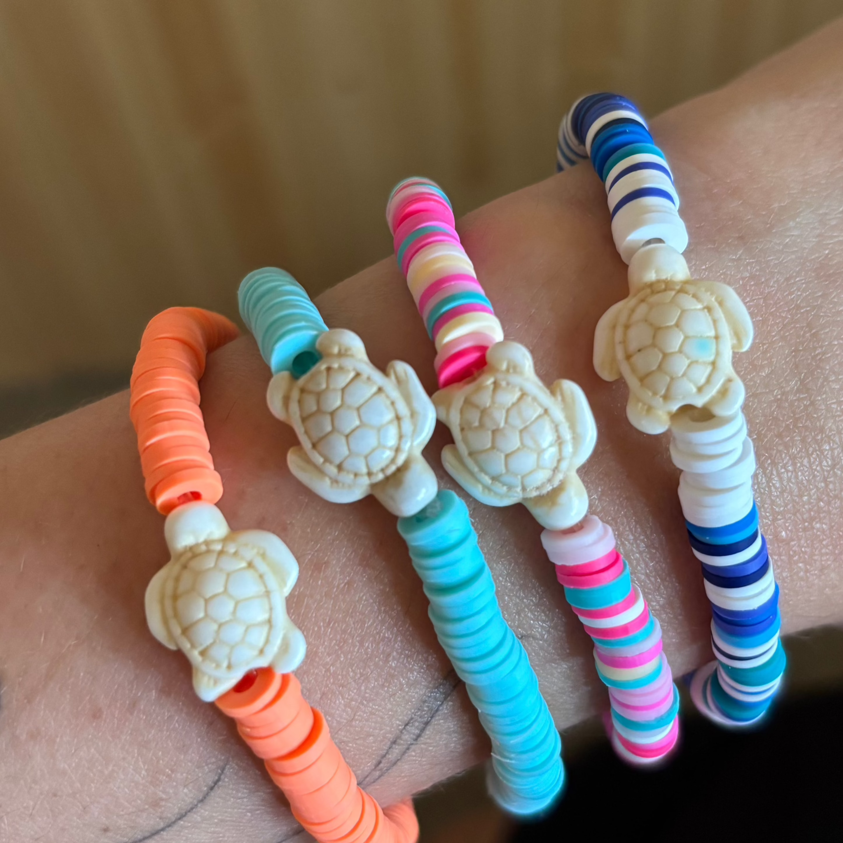 Colourful turtle-themed bracelets on a wrist with a neutral background