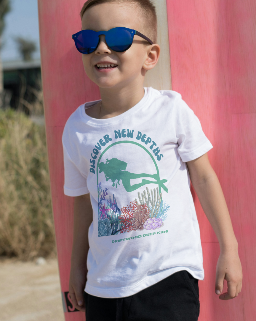 Child wearing a white t-shirt with a graphic design, standing in front of a pink wall.