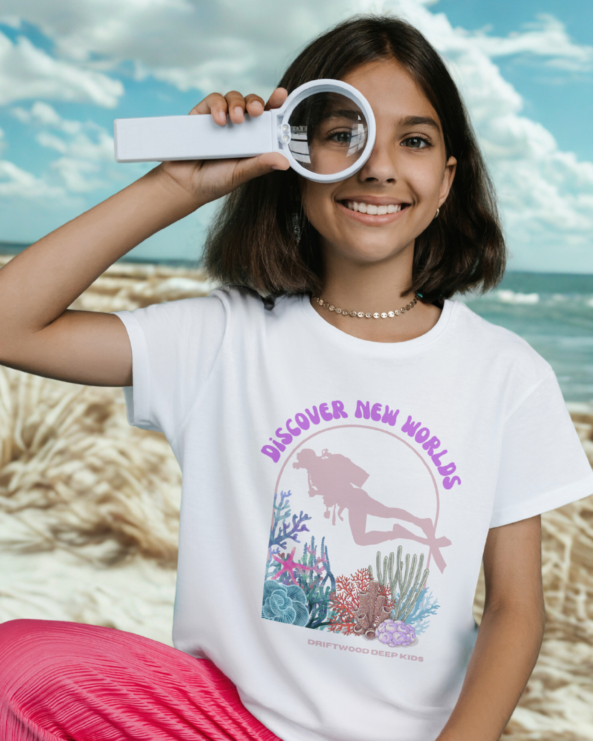 Girl wearing a t-shirt with a mermaid graphic and text on a beach