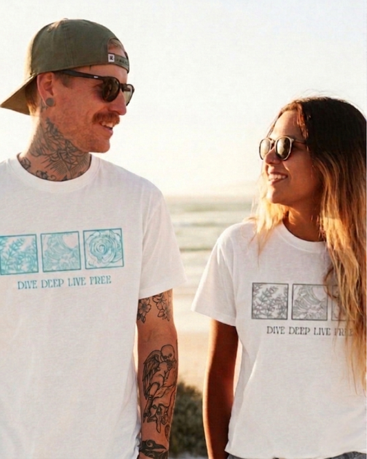 Two people wearing white t-shirts with graphic designs on a beach.