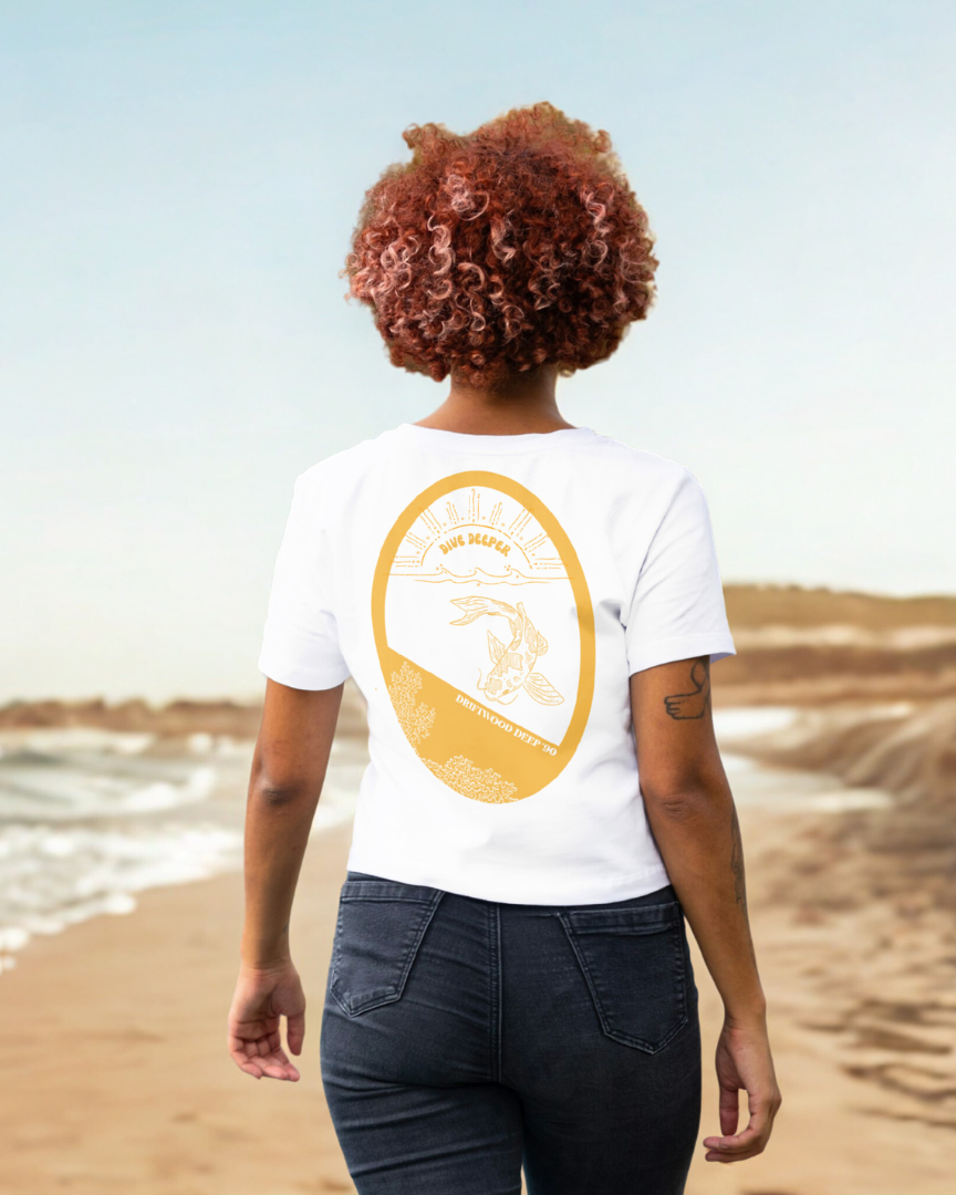 Person wearing a white t-shirt with a yellow graphic on the beach