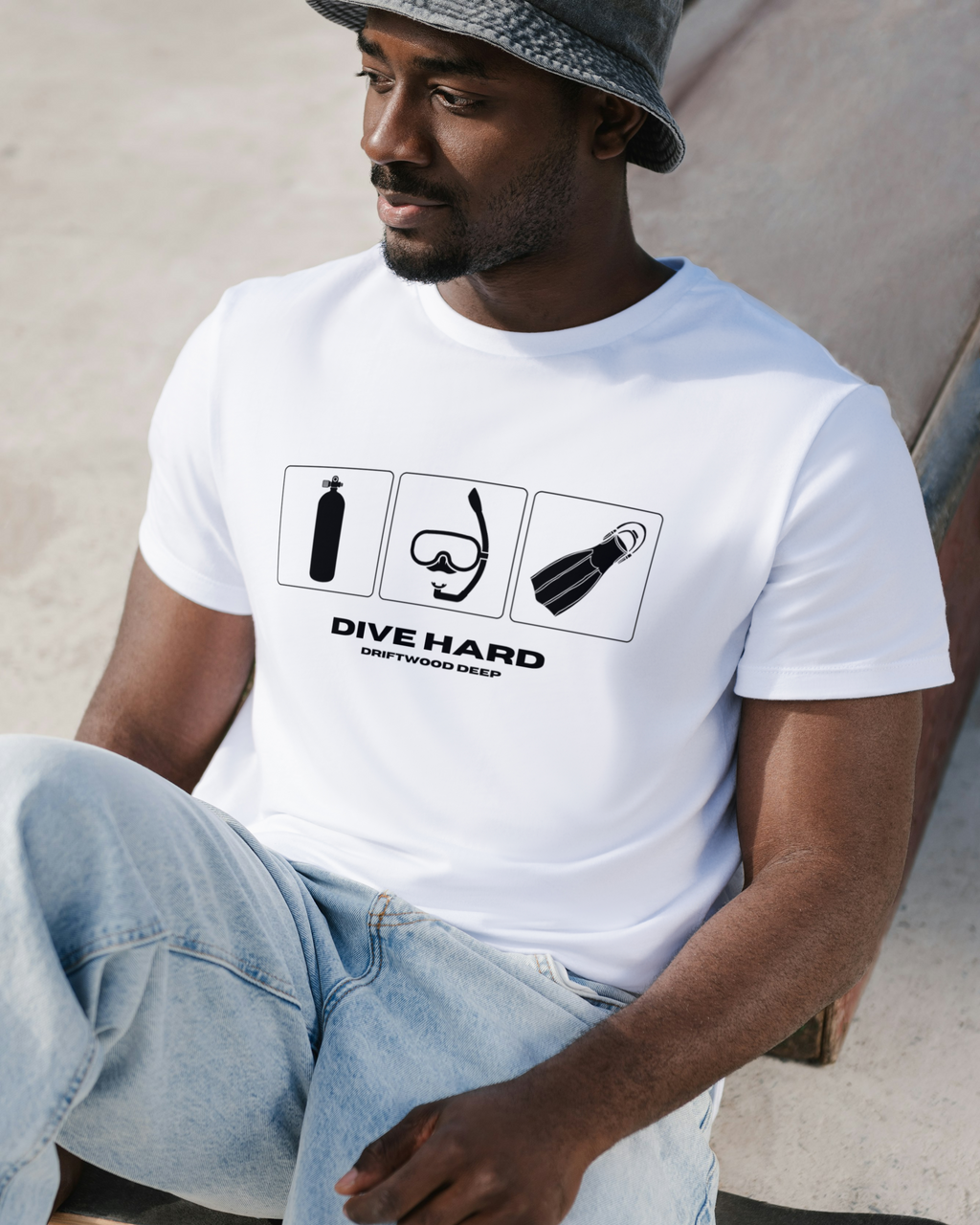 Man wearing a white t-shirt with diving-themed graphics and text, sitting on a skateboard.