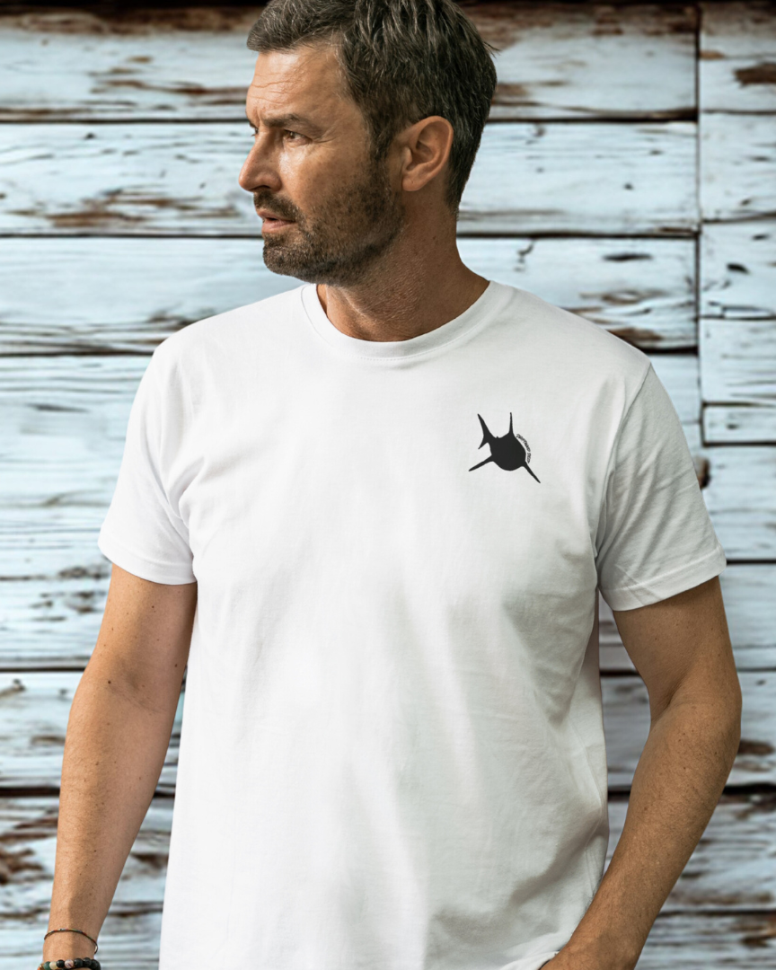 Man wearing a white t-shirt with a black logo against a rustic wooden background