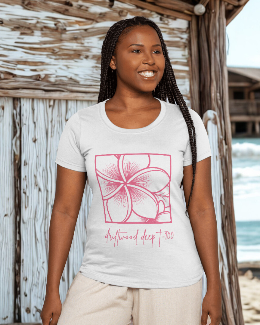 Woman wearing a white t-shirt with a pink floral design on a beach.