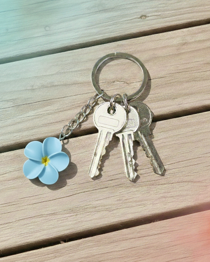 Keychain with keys and a blue flower charm on wooden surface