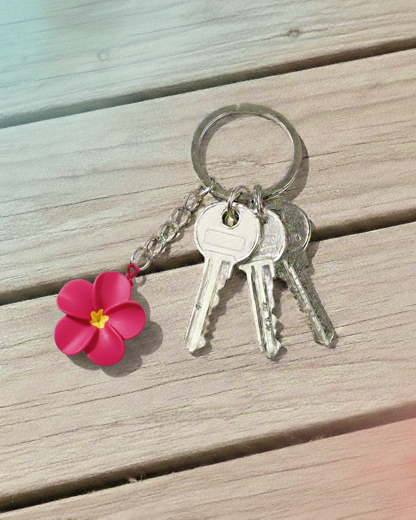 Keychain with pink flower charm and keys on a wooden surface