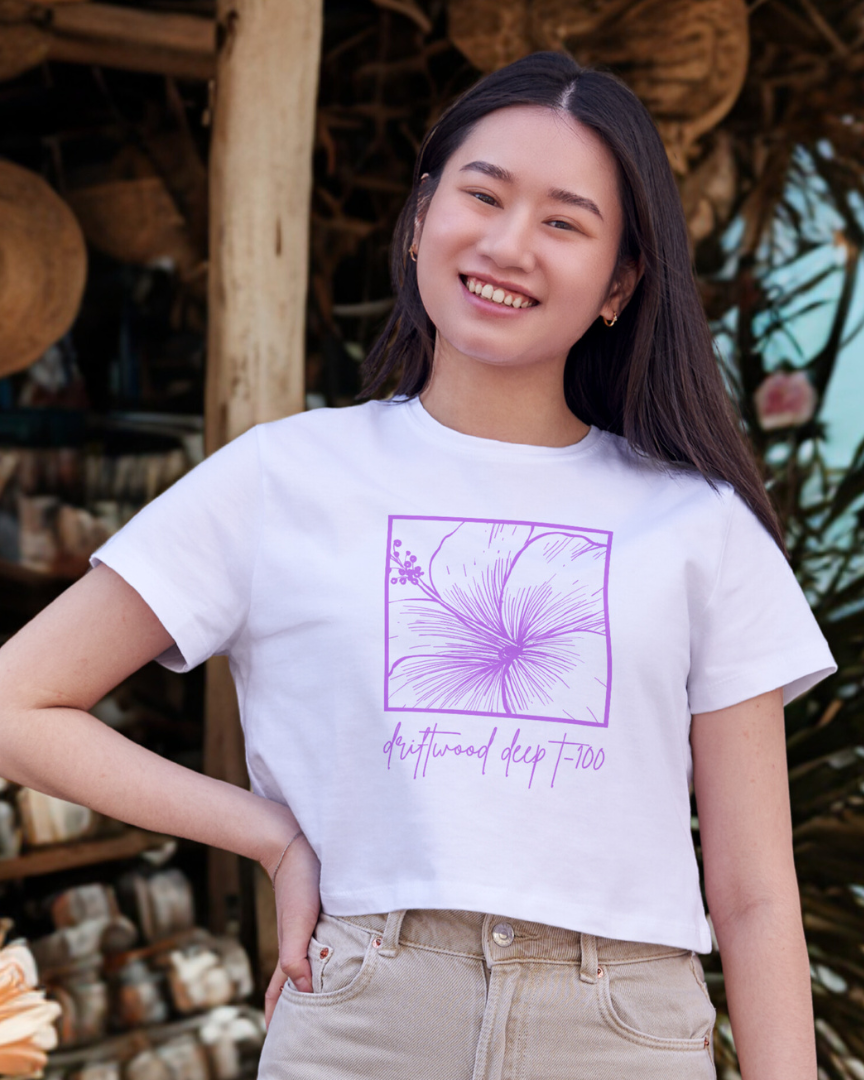 Person wearing a white t-shirt with a purple graphic design in an outdoor setting