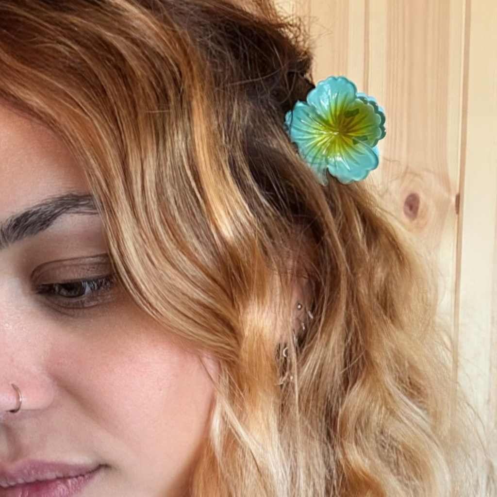 Woman with wavy hair wearing a blue flower hair clip against a wooden background