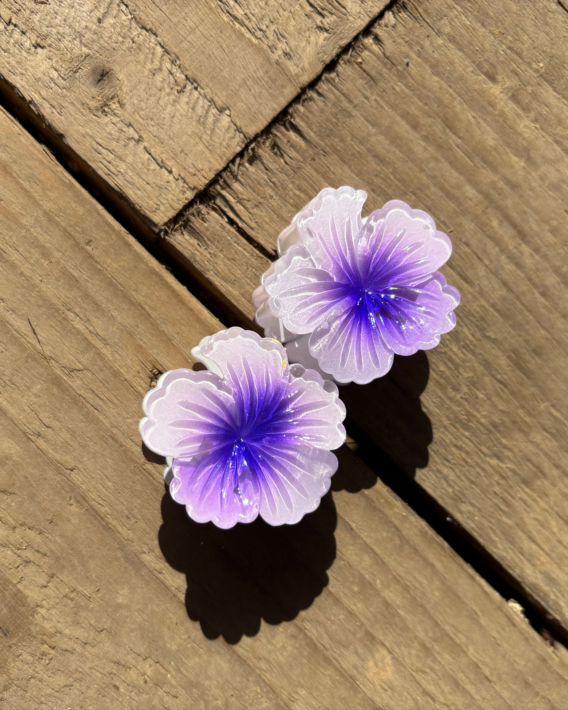 Purple flower-shaped hair clips on a wooden surface