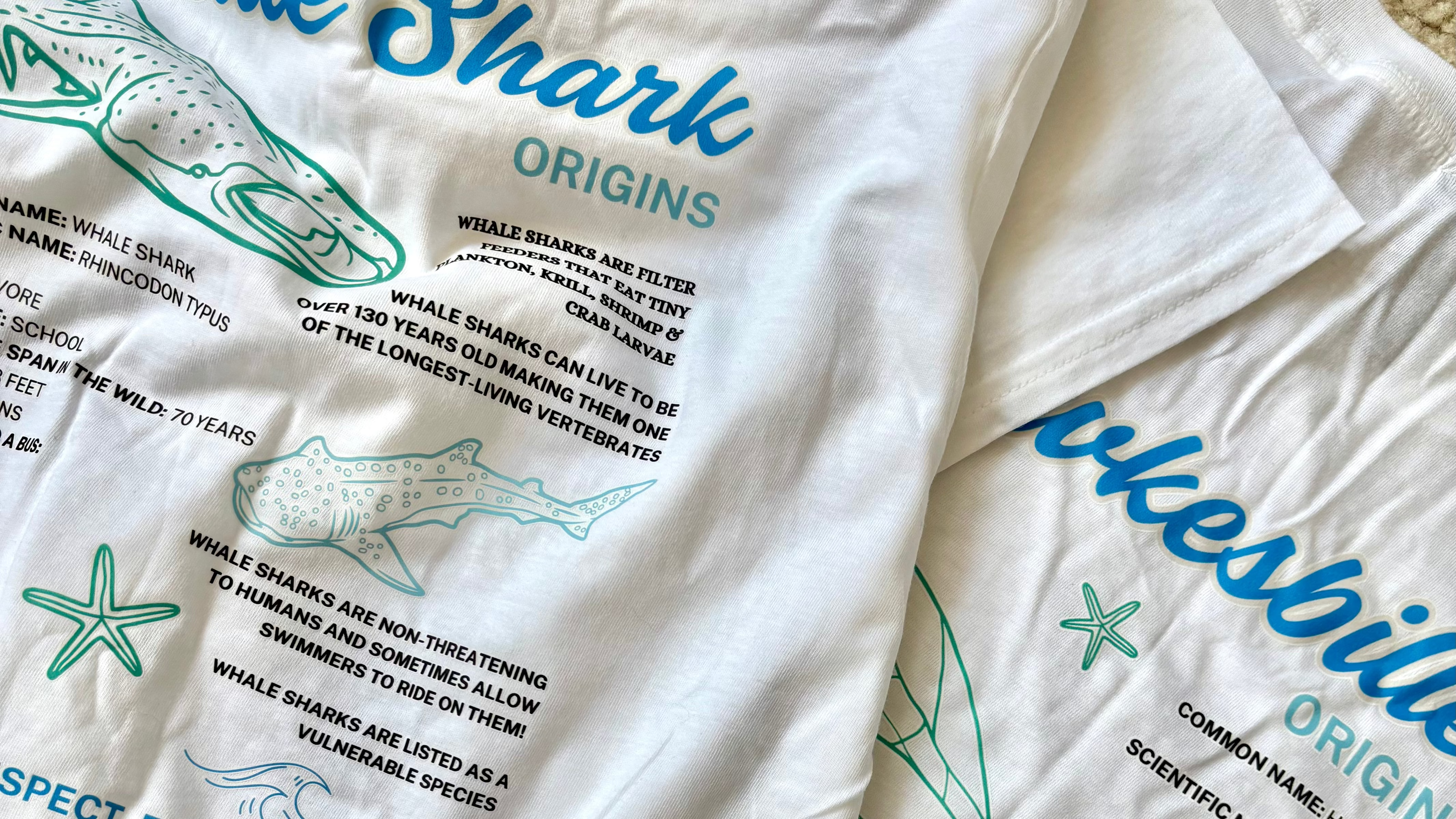 White t-shirt with educational graphics and text about whale sharks and turtles on a white background.