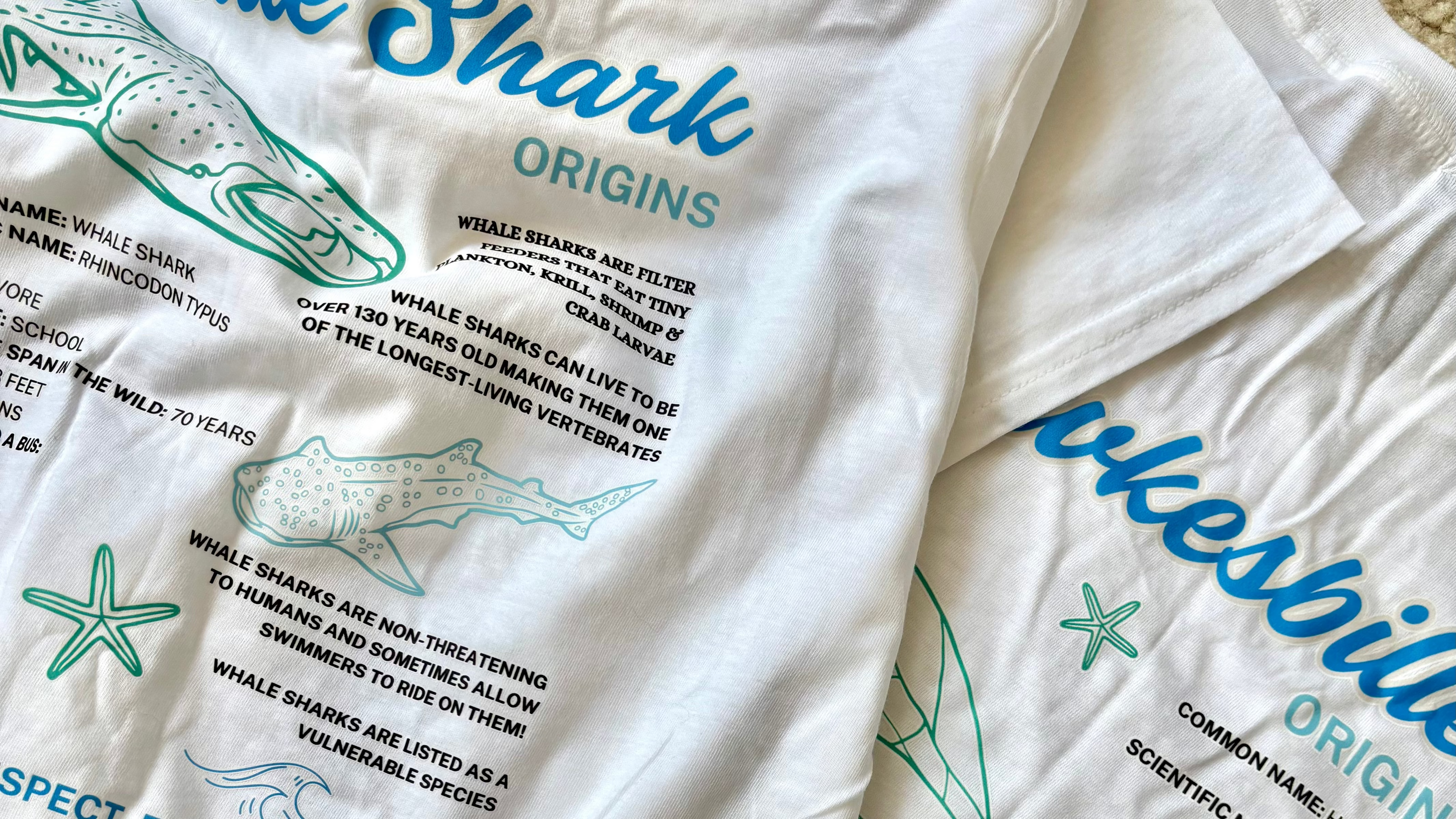 White t-shirt with educational graphics and text about whale sharks and turtles on a white background.