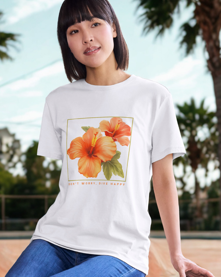 Person wearing a white t-shirt with a floral design, sitting outdoors with palm trees in the background.