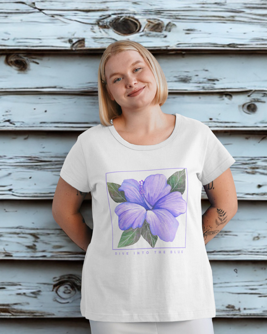 Person wearing a white t-shirt with a purple flower graphic against a wooden background
