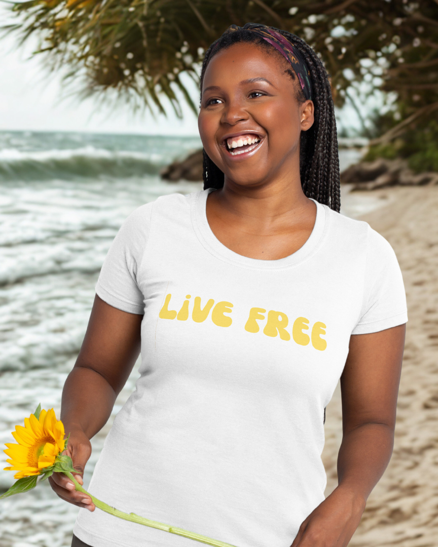 Woman on a beach holding a sunflower wearing a 'Live Free' t-shirt.