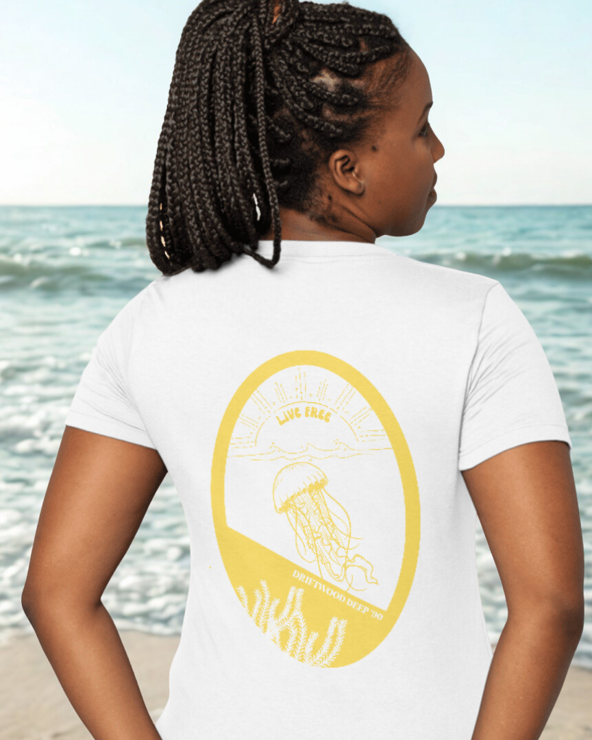 Person wearing a white t-shirt with a yellow graphic on the beach
