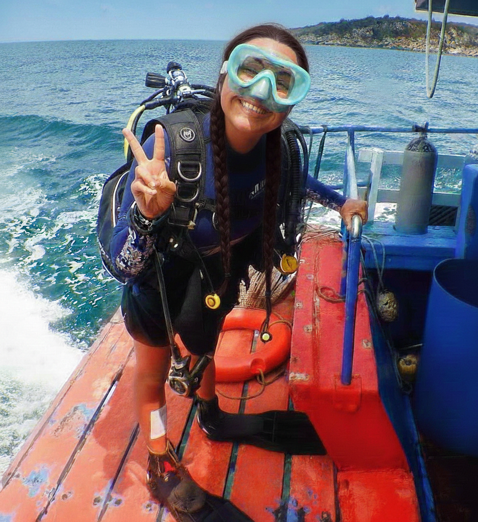 Person on a boat wearing diving gear with a scenic background