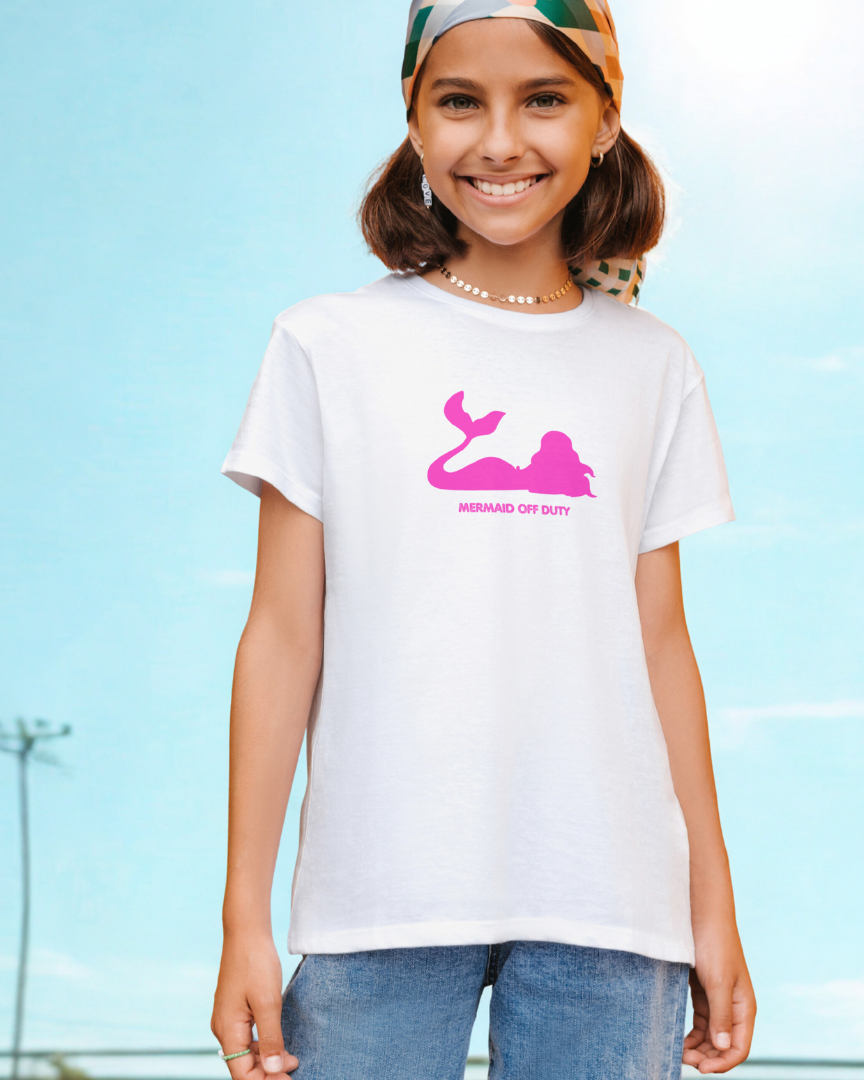 Young girl wearing a white t-shirt with a pink graphic design outdoors.