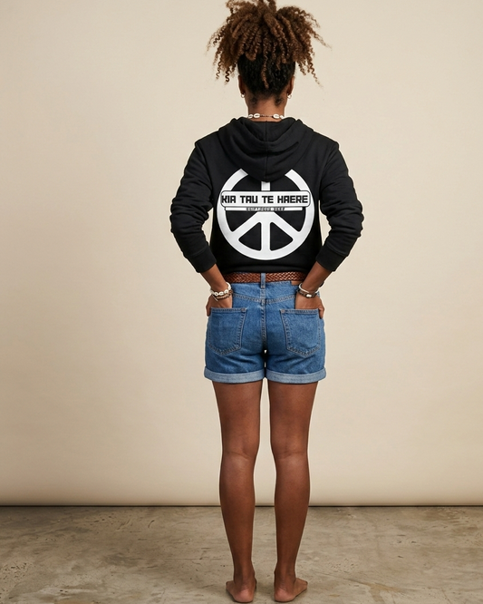 Person wearing a black hoodie with a peace symbol design on the back, standing against a plain background.