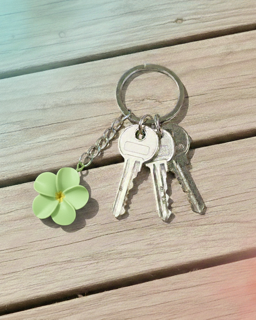 Keychain with keys and a green flower charm on a wooden surface