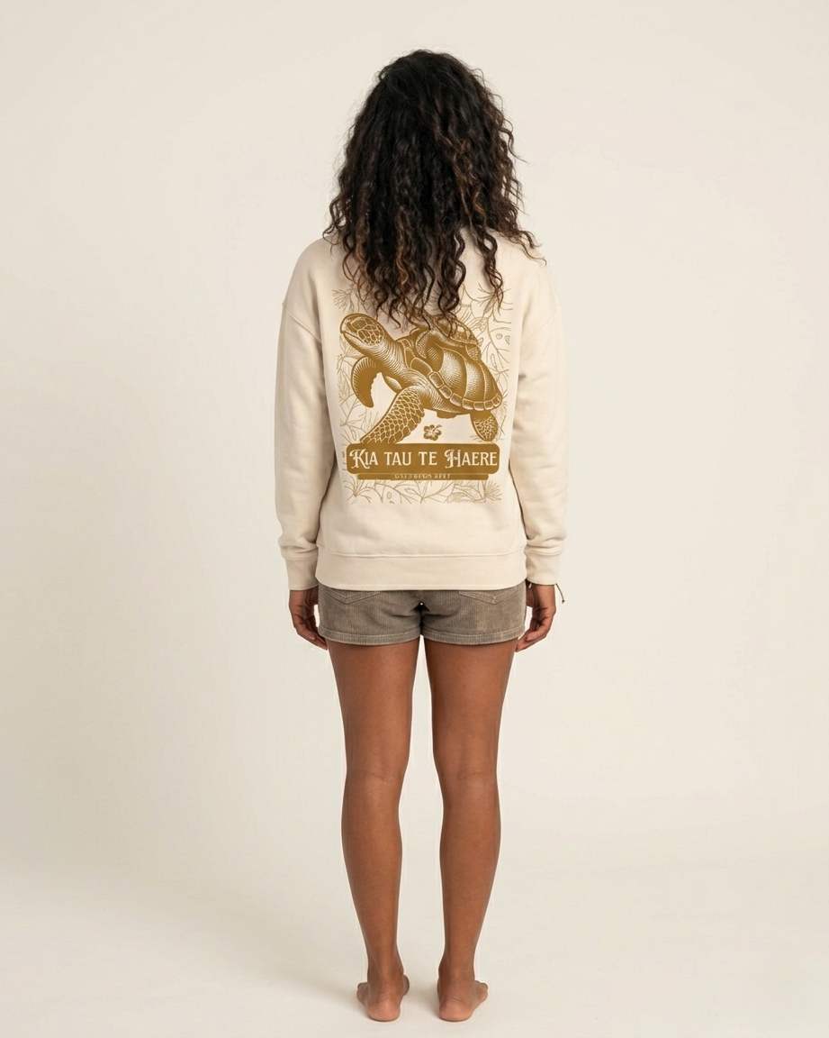 Person wearing a beige sweatshirt with a graphic design on the back against a plain background