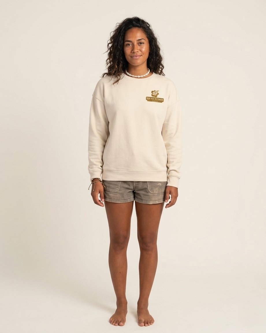 Person wearing a beige sweatshirt with a logo on a plain background