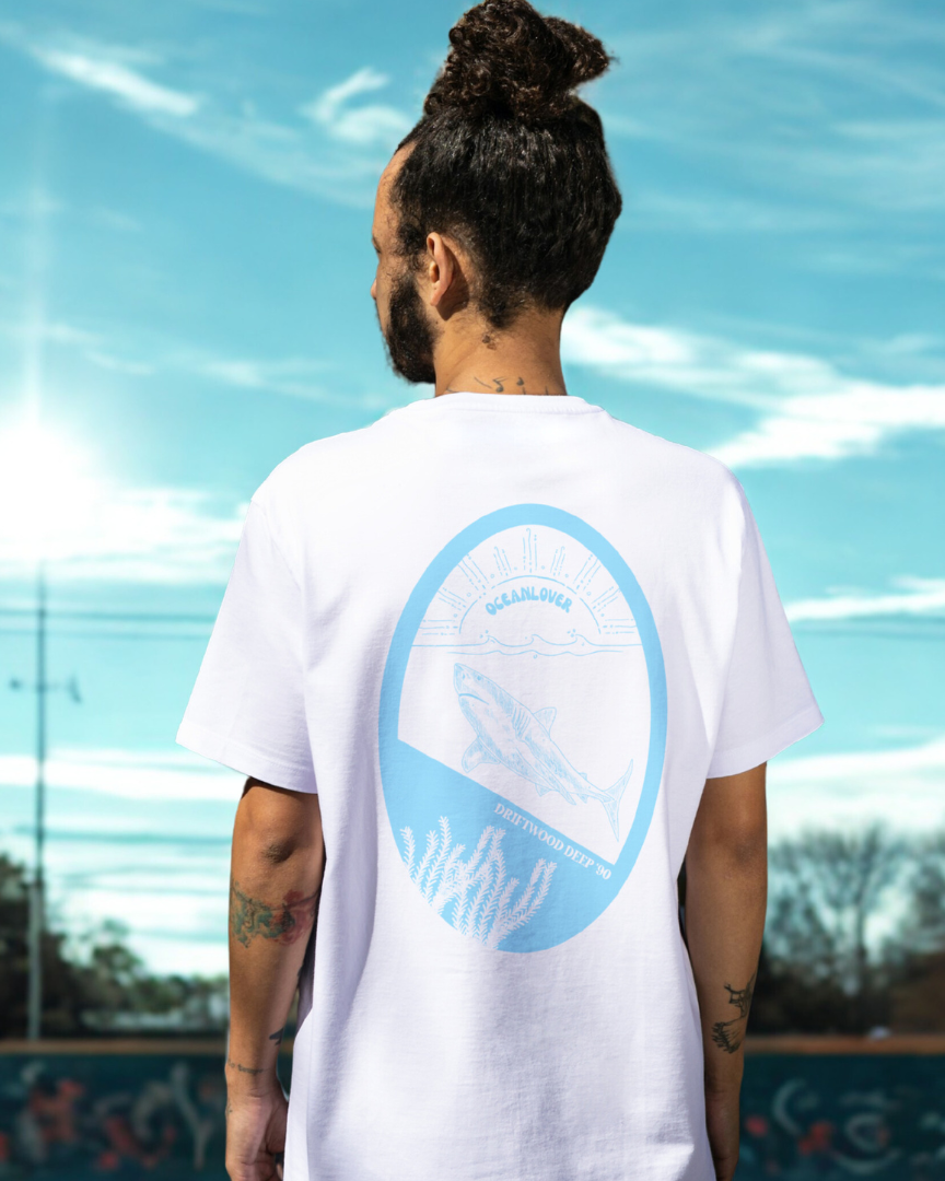 Person wearing a white t-shirt with a blue graphic design outdoors