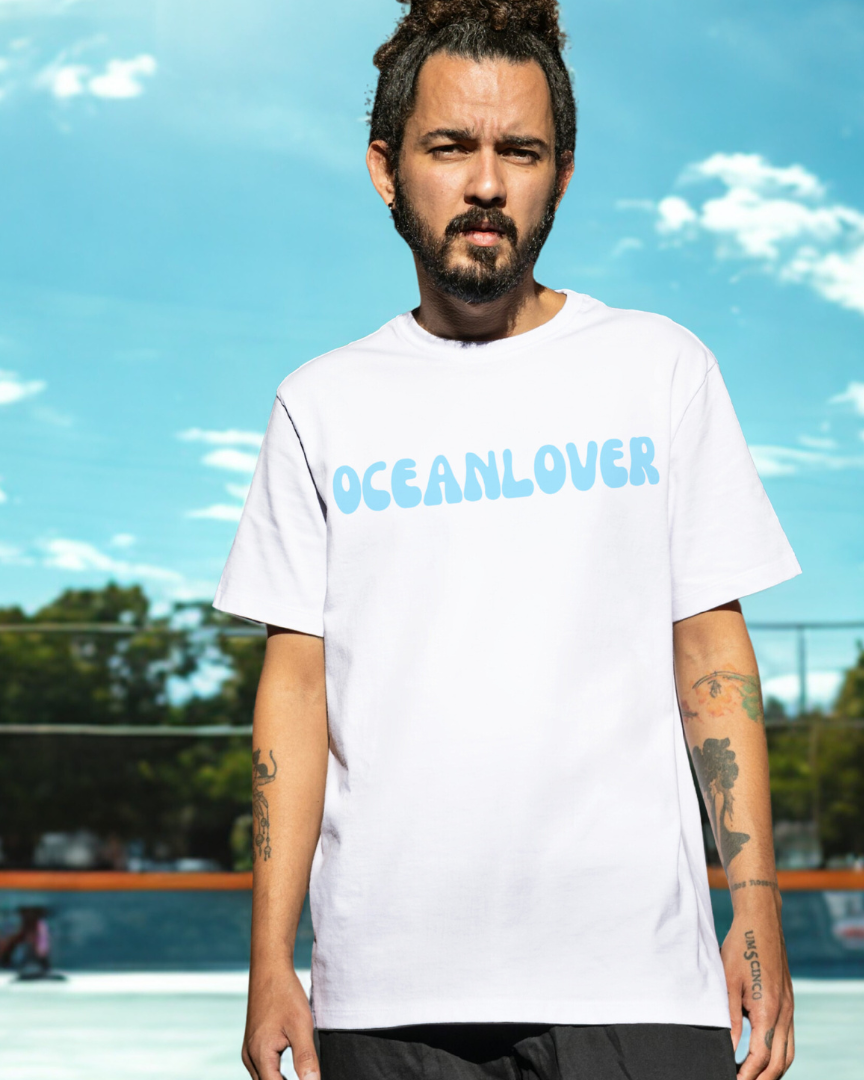 Person wearing a white 'OCEANLOVER' t-shirt against a blue sky with clouds.