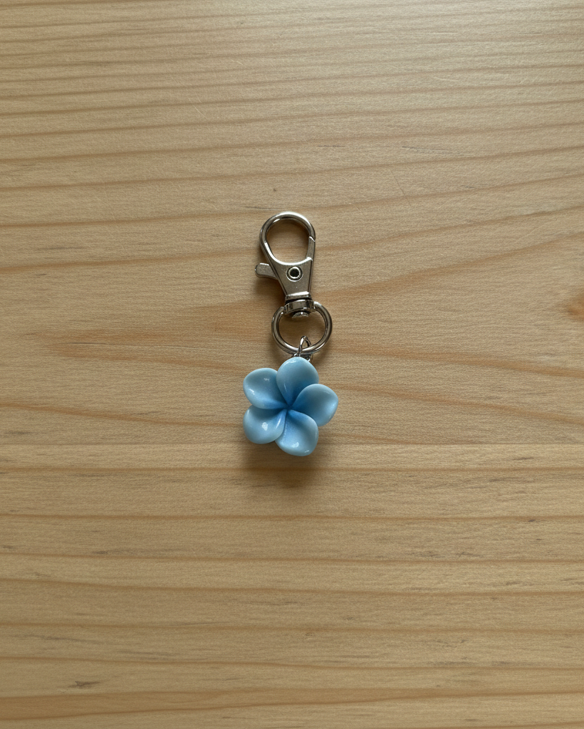 Blue flower-shaped keychain charm on a wooden surface