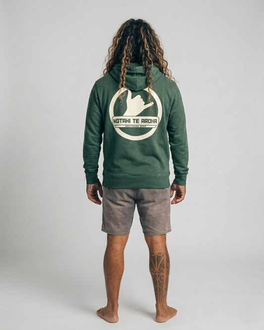 Person wearing a green hoodie with a logo on the back, standing against a plain background