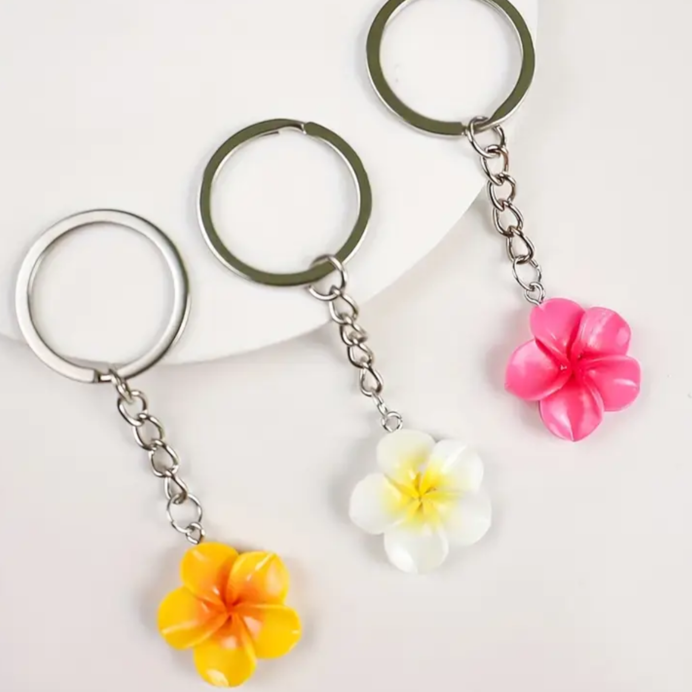 Three floral keychains with different coloured flowers on a white background