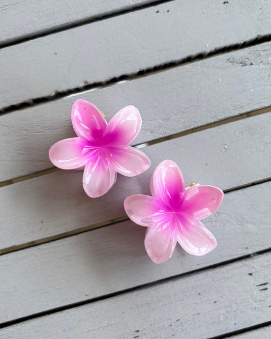 Pink flower-shaped hair clips on a wooden surface