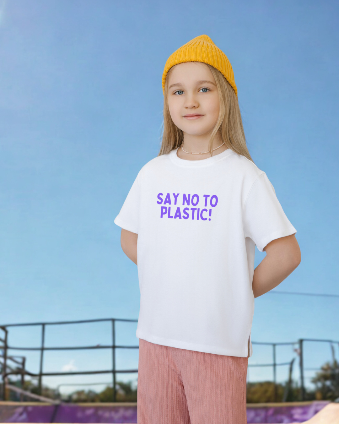 Young girl wearing a white t-shirt with 'Say No to Plastic!' text against a clear blue sky.