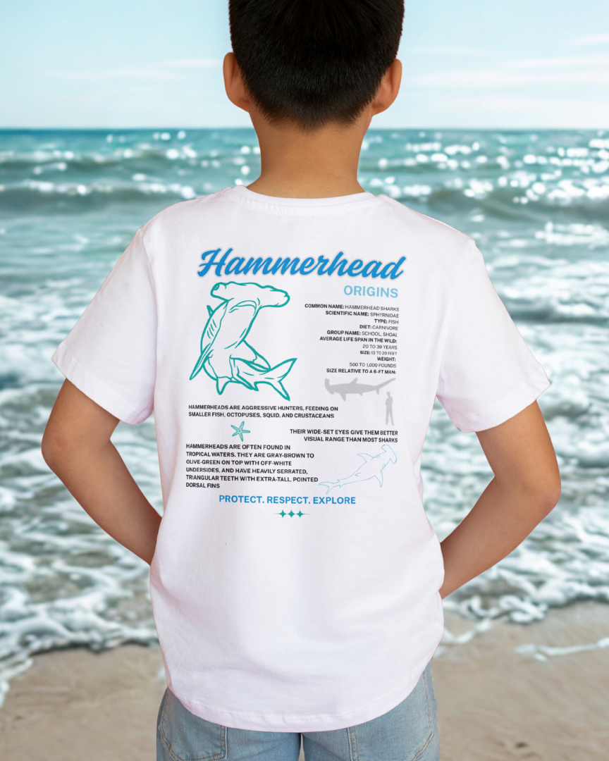 Person wearing a white t-shirt with a hammerhead shark design on the beach