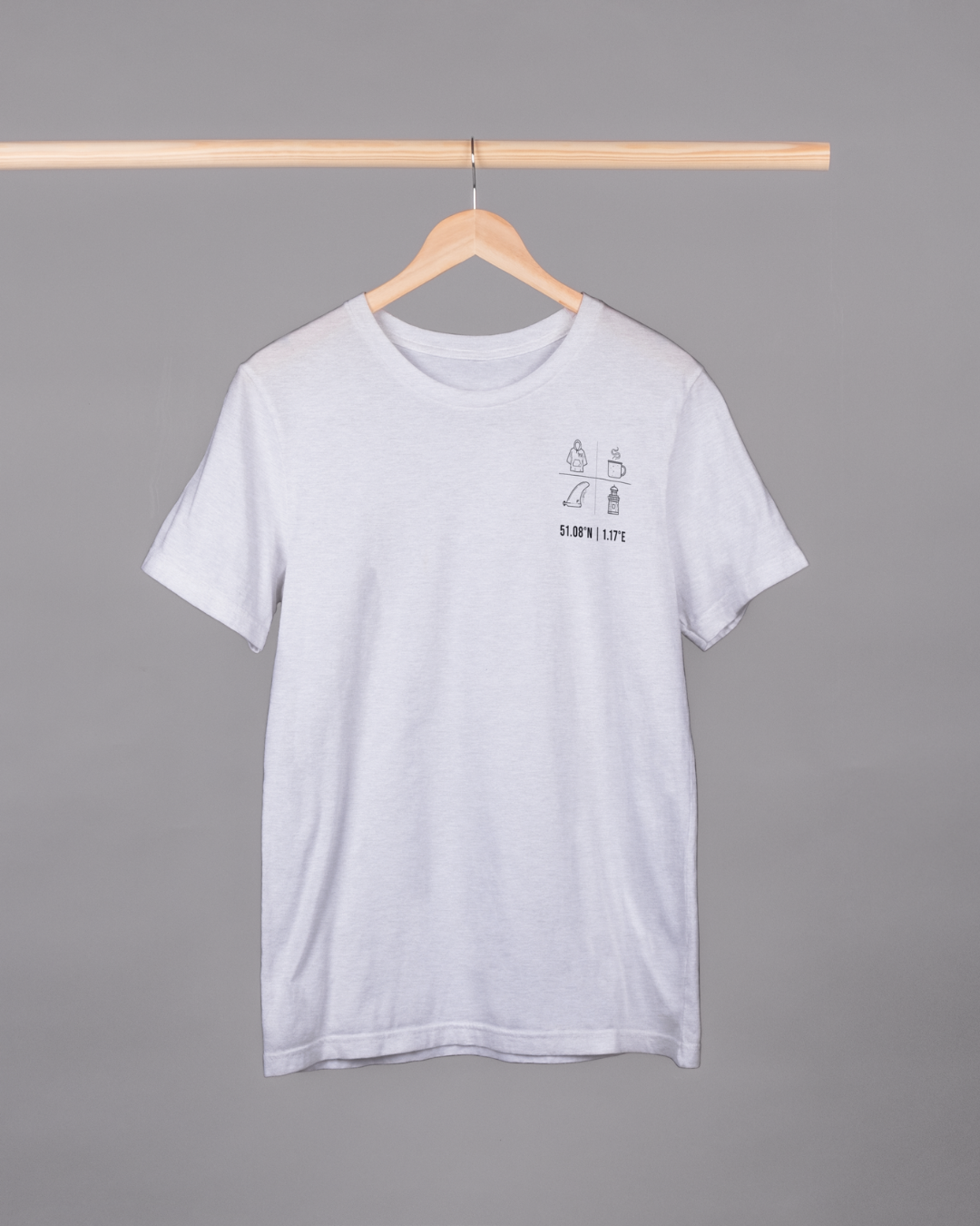 White t-shirt with a small graphic on a hanger against a gray background