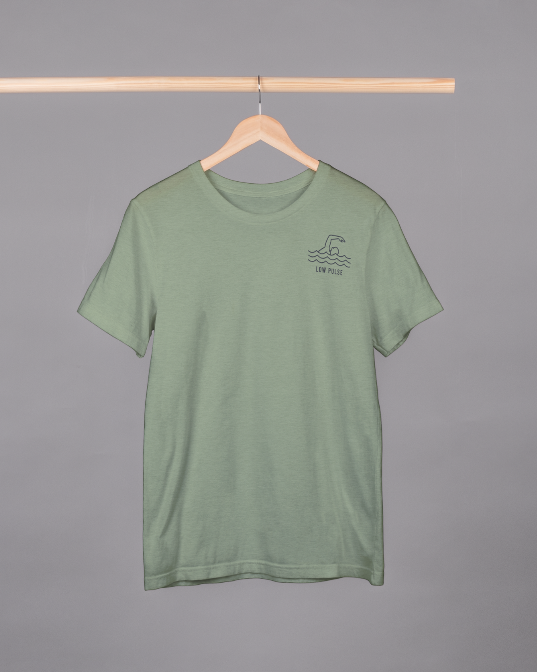Green t-shirt with a small logo on a hanger against a gray background