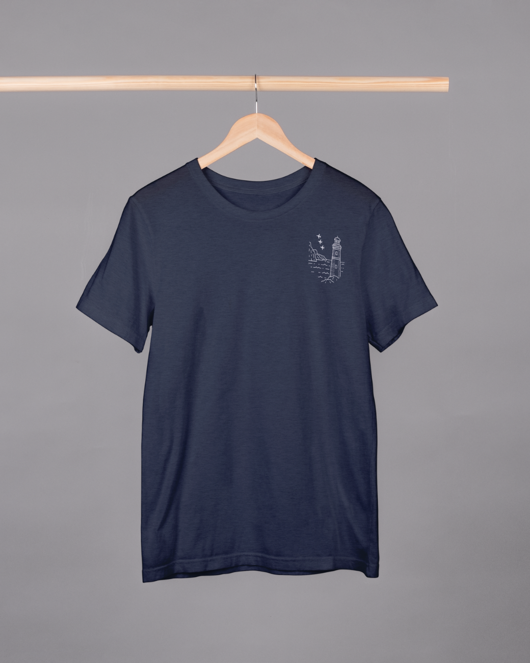 Navy blue t-shirt with a small graphic on a hanger against a gray background
