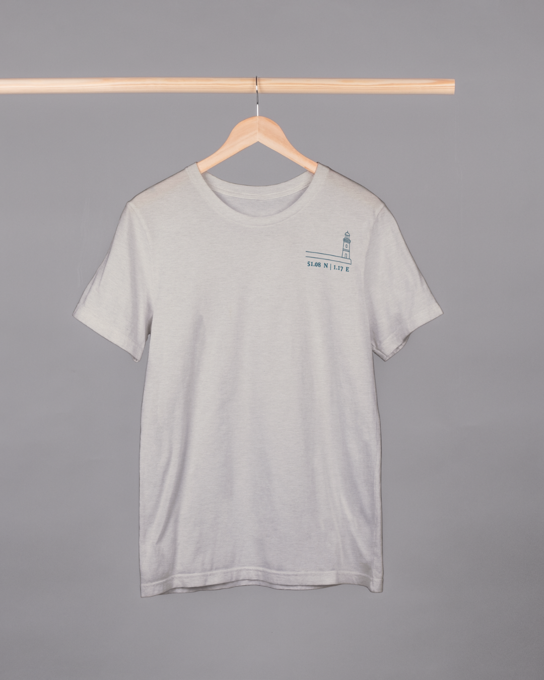 Gray t-shirt with a small logo on a hanger against a gray background
