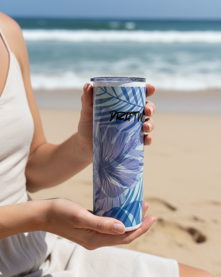 Person holding a blue floral-patterned tumbler on a beach