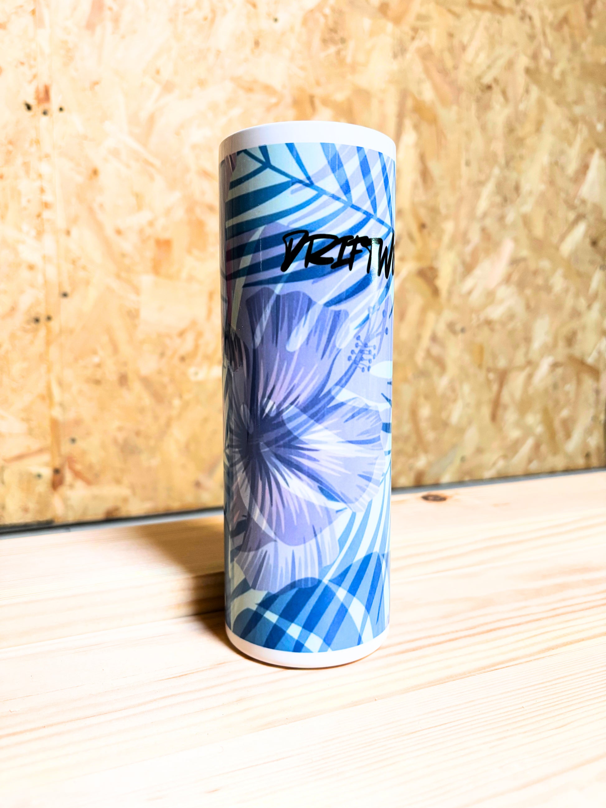 Tall cylindrical container with blue floral design on a wooden surface.
