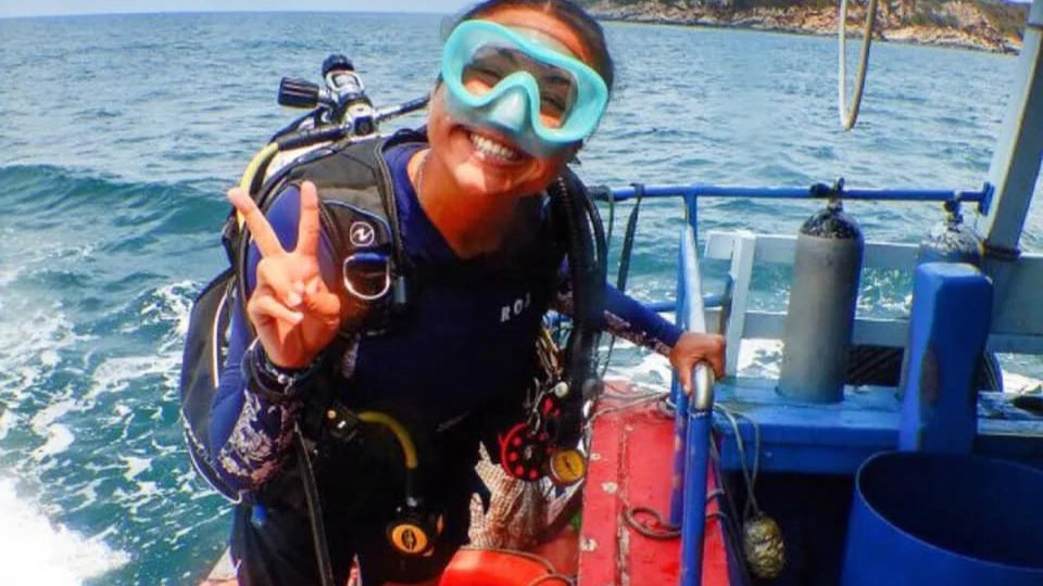 Person in scuba diving gear on a boat with a scenic background